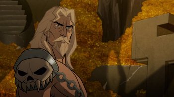 Movie still from “Justice League: Warworld” (2023), directed by Jeff Wamester – A man with a long beard is standing in front of a cave; Close Up shot, High angle