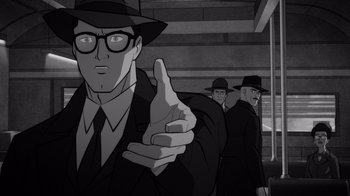 Movie still from “Justice League: Warworld” (2023), directed by Jeff Wamester – A man in a suit and a hat pointing to the camera; Medium shot, Over the shoulder angle
