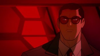 Movie still from “Justice League: Warworld” (2023), directed by Jeff Wamester – A man in a suit and sunglasses in front of a red background; Close Up shot, Low angle