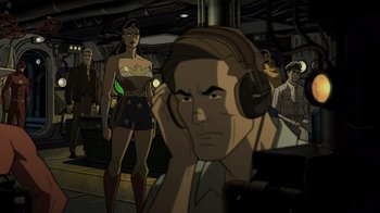 Movie still from “Justice Society: World War II” (2021), directed by Jeff Wamester – A man with headphones is listening intently to a show; Medium shot, Over the shoulder angle