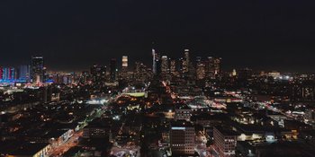 Movie still from “KSI: In Real Life” (2023), directed by Wes Pollitt – A view of a large city at night time; Extreme Wide shot, High angle