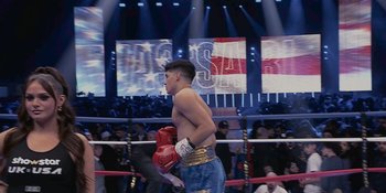 Movie still from “KSI: In Real Life” (2023), directed by Wes Pollitt – A man in a boxing ring wearing a red glove; Medium shot, Over the shoulder angle