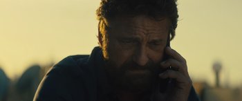 Movie still from “Kandahar” (2023), directed by Ric Roman Waugh – A person talking on a cell phone; Close Up shot, Low angle
