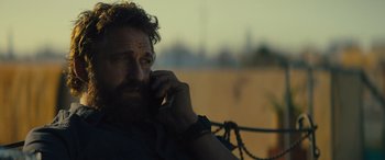 Movie still from “Kandahar” (2023), directed by Ric Roman Waugh – A person talking on a cell phone; Close Up shot, Over the shoulder angle