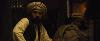 Movie still from “Kandahar” (2023), directed by Ric Roman Waugh – A man with a turban on his head; Medium shot, Over the shoulder angle