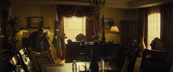 Movie still from “Kandahar” (2023), directed by Ric Roman Waugh – A living room with a desk , chair , and a lamp; Wide shot, Low angle