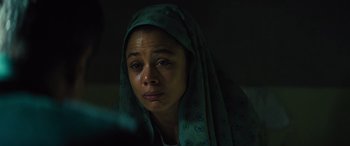 Movie still from “Kandahar” (2023), directed by Ric Roman Waugh – A woman with a green head covering crying; Close Up shot, High angle