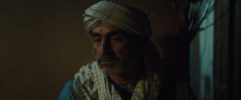 Movie still from “Kandahar” (2023), directed by Ric Roman Waugh – An older man wearing a turban is looking at the camera; Close Up shot, Over the shoulder angle