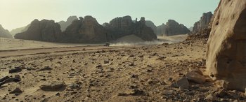 Movie still from “Kandahar” (2023), directed by Ric Roman Waugh – A truck driving on a dirt road in the middle of the desert; Extreme Wide shot, High angle