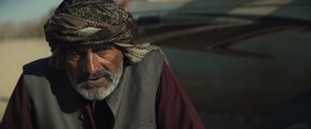 Movie still from “Kandahar” (2023), directed by Ric Roman Waugh – An older man wearing a turban and a vest; Close Up shot, Over the shoulder angle