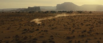 Movie still from “Kandahar” (2023), directed by Ric Roman Waugh – A truck is driving through the desert near a mountain range; Extreme Wide shot, High angle