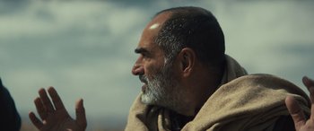 Movie still from “Kandahar” (2023), directed by Ric Roman Waugh – An older man with a beard is looking into the distance; Close Up shot, Low angle