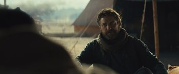 Movie still from “Kandahar” (2023), directed by Ric Roman Waugh – A man with a beard is sitting in a tent; Close Up shot, Over the shoulder angle