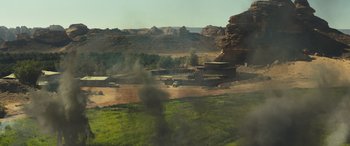 Movie still from “Kandahar” (2023), directed by Ric Roman Waugh – An image of an open field with smoke coming out of it; Extreme Wide shot, High angle