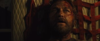 Movie still from “Kandahar” (2023), directed by Ric Roman Waugh – A person with blood on his face; Close Up shot, Overhead angle