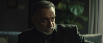 Movie still from “Kandahar” (2023), directed by Ric Roman Waugh – An older man with a beard and mustache looking at the camera; Close Up shot, Over the shoulder angle