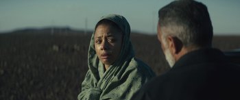 Movie still from “Kandahar” (2023), directed by Ric Roman Waugh – A woman wrapped in a blanket is looking at a man; Close Up shot, Over the shoulder angle