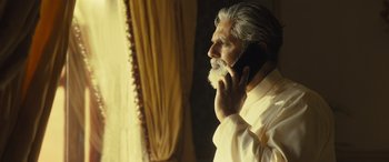 Movie still from “Kandahar” (2023), directed by Ric Roman Waugh – An older man talking on a cell phone; Medium shot, Low angle