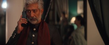 Movie still from “Khufiya” (2023), directed by Vishal Bhardwaj – An older man with white hair and a red scarf; Medium shot, Over the shoulder angle
