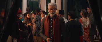 Movie still from “Khufiya” (2023), directed by Vishal Bhardwaj – A man with a gray beard wearing a red scarf; Medium shot, Low angle