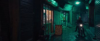 Movie still from “Khufiya” (2023), directed by Vishal Bhardwaj – A man sitting on the ground in front of a store at night; Extreme Wide shot, High angle