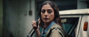 Movie still from “Khufiya” (2023), directed by Vishal Bhardwaj – A woman holding a walkie talkie while standing next to a car; Close Up shot, High angle