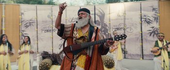 Movie still from “Khufiya” (2023), directed by Vishal Bhardwaj – An older man with a beard and a guitar; Medium shot, Low angle