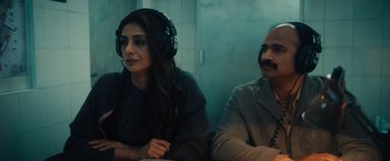Movie still from “Khufiya” (2023), directed by Vishal Bhardwaj – A woman wearing headphones sitting next to a man wearing headphones; Medium shot, Over the shoulder angle