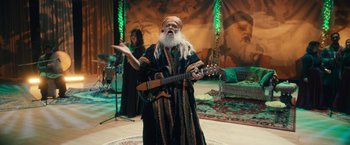 Movie still from “Khufiya” (2023), directed by Vishal Bhardwaj – An old man with long white beard playing a guitar; Wide shot, Low angle