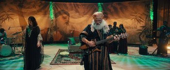 Movie still from “Khufiya” (2023), directed by Vishal Bhardwaj – An old man playing a guitar on stage in front of an audience; Wide shot, High angle