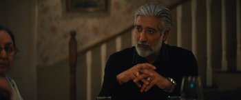 Movie still from “Khufiya” (2023), directed by Vishal Bhardwaj – An older man sitting at a table with his fingers crossed; Close Up shot, Over the shoulder angle