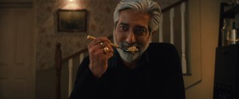 Movie still from “Khufiya” (2023), directed by Vishal Bhardwaj – An older man with white hair and a beard is holding a wooden spoon in his mouth; Close Up shot, Low angle