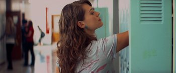 Movie still from “Kick-Ass” (2010), directed by Matthew Vaughn – A woman standing in a room with her arms outstreched; Close Up shot, Over the shoulder angle