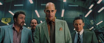 Movie still from “Kick-Ass” (2010), directed by Matthew Vaughn – A man in a suit and tie standing in a room; Close Up shot, Low angle