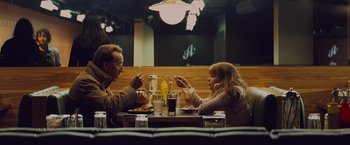 Movie still from “Kick-Ass” (2010), directed by Matthew Vaughn – A man and a woman sitting at a table eating food; Medium shot, Over the shoulder angle