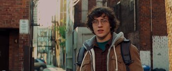 Movie still from “Kick-Ass” (2010), directed by Matthew Vaughn – A young man wearing glasses and a brown jacket; Close Up shot, Over the shoulder angle