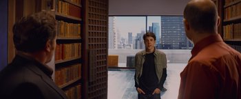 Movie still from “Kick-Ass” (2010), directed by Matthew Vaughn – A man standing in front of a book shelf in a library; Medium shot, Over the shoulder angle