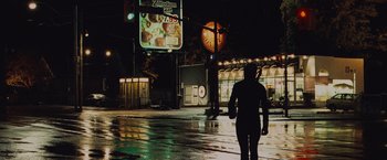 Movie still from “Kick-Ass” (2010), directed by Matthew Vaughn – A person walking down a street at night; Wide shot, Low angle