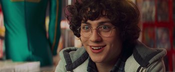 Movie still from “Kick-Ass” (2010), directed by Matthew Vaughn – A person with glasses smiling for the camera; Close Up shot, Over the shoulder angle