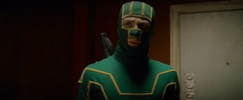 Movie still from “Kick-Ass” (2010), directed by Matthew Vaughn – A man in a green and yellow costume with an arrow; Close Up shot, Low angle