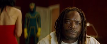 Movie still from “Kick-Ass” (2010), directed by Matthew Vaughn – A person with dreadlocks looking at the camera; Close Up shot, Low angle