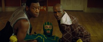 Movie still from “Kick-Ass” (2010), directed by Matthew Vaughn – A group of men standing next to each other in a room; Medium shot, Low angle