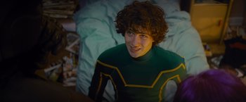 Movie still from “Kick-Ass” (2010), directed by Matthew Vaughn – A man with curly hair wearing a green and yellow costume; Medium shot, Over the shoulder angle