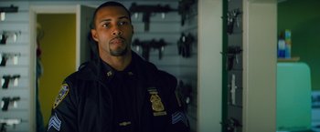 Movie still from “Kick-Ass” (2010), directed by Matthew Vaughn – A police officer in uniform looking into the camera; Medium shot, Over the shoulder angle