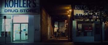 Movie still from “Kick-Ass” (2010), directed by Matthew Vaughn – A person walking down a street at night; Extreme Wide shot, Low angle