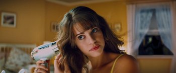 Movie still from “Kick-Ass” (2010), directed by Matthew Vaughn – A beautiful young lady holding a blow dryer in front of her face; Close Up shot, Low angle
