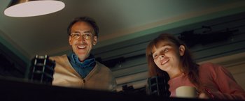 Movie still from “Kick-Ass” (2010), directed by Matthew Vaughn – A man and a woman smile for the camera; Medium shot, Low angle