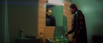 Movie still from “Kick-Ass” (2010), directed by Matthew Vaughn – A man looking at himself in the mirror in a bathroom; Medium shot, Low angle