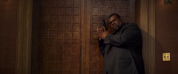 Movie still from “Kick-Ass” (2010), directed by Matthew Vaughn – A man in a suit holding a gun in his hand; Medium shot, Low angle