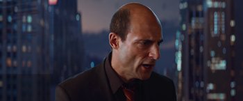 Movie still from “Kick-Ass” (2010), directed by Matthew Vaughn – A bald man in a suit and red neck tie; Close Up shot, Over the shoulder angle